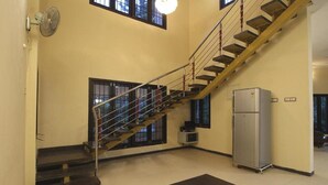 Un escalier avec une rampe métallique, un réfrigérateur et un petit appareil de climatisation.