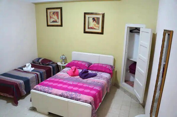 Cozy bedroom with a comfortable bed and two smaller beds, featuring a stylish bedspread and framed artwork.