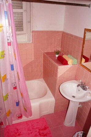 Bathroom features a bathtub, sink, and shower, with a potted plant and towels nearby.