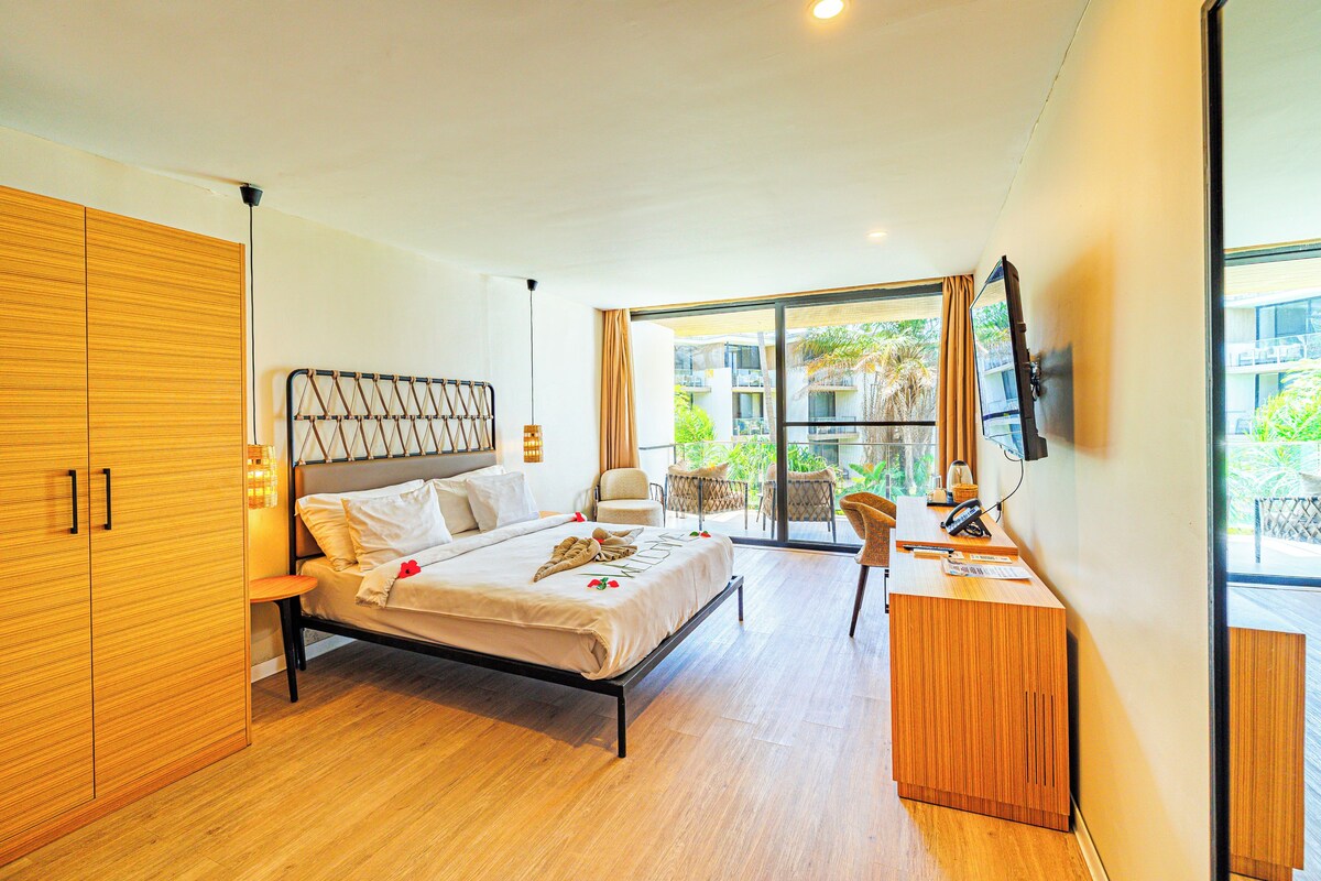 A modern bedroom with a bed, wooden wardrobe, desk, and a balcony with outdoor furniture.