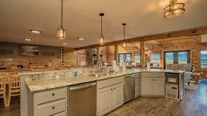 A spacious kitchen with wooden cabinets, granite countertops, and pendant lighting. - PinnacleView: POOL, Breathtaking Views, Movie Room, Games, Hot Tub, Wifi (Sevierville)
