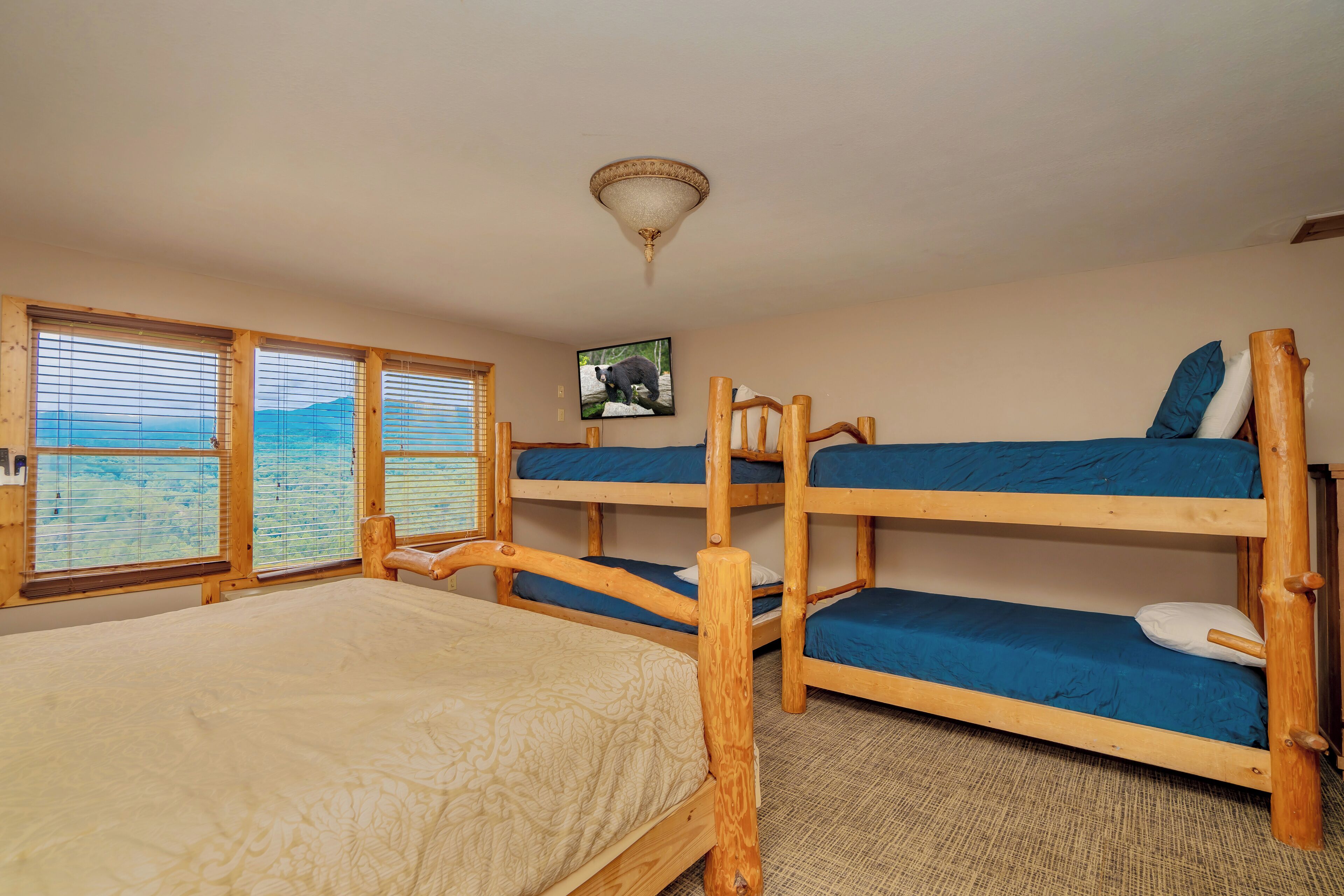 Ein Zimmer mit Etagenbetten, einem Bett und Bergblick durch große Fenster.