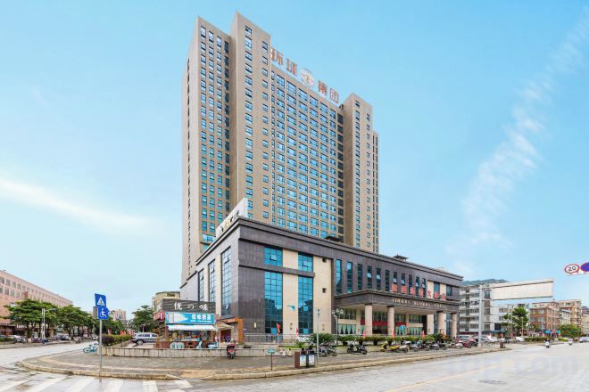 A high-rise hotel with a modern facade, a central entrance, and a parking area in front.