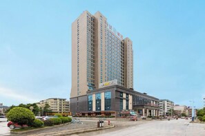 A high-rise hotel with multiple floors, a central entrance, and a parking area in front. - Jingxi Global Hotel (Jingxi)