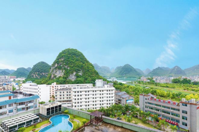 Un quartier résidentiel comprenant un grand immeuble, une piscine et un paysage montagneux en arrière-plan.