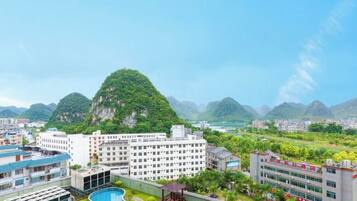A residential area with a large building, a swimming pool, and a mountainous backdrop.