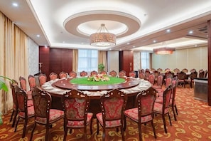 A conference room with a round table, chairs, and a chandelier.