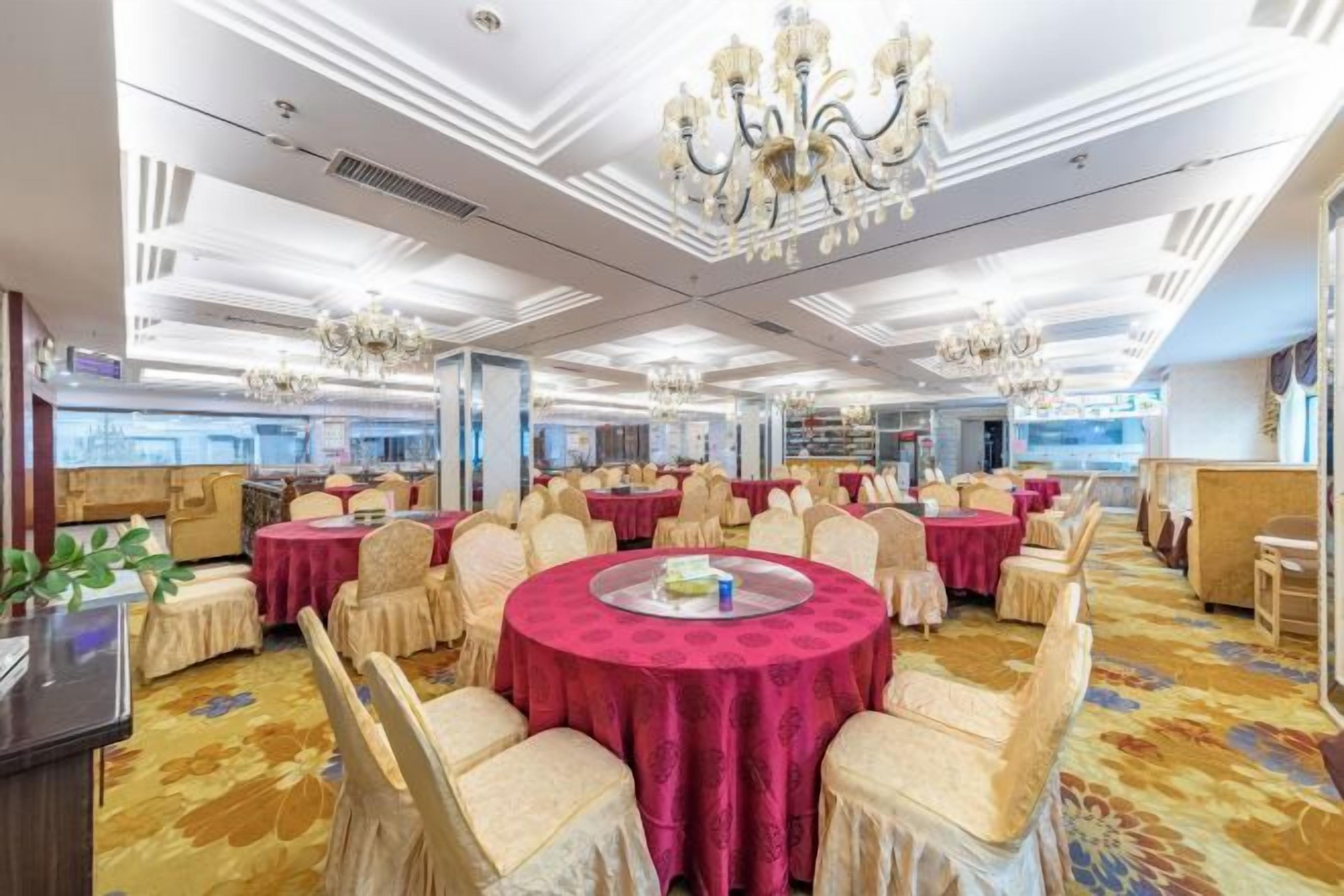 A banquet hall with round tables, chairs, and chandeliers.