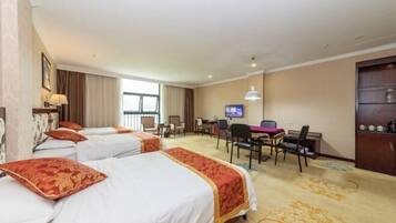 Una habitación de hotel con tres camas, un escritorio, televisor y minibar.