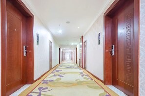 A hotel corridor with wooden doors, a patterned carpet, and a long hallway. - Jingxi Global Hotel (Jingxi)