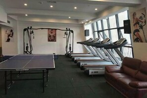 Une salle de sport équipée de tapis de course, d’une table de ping-pong et de matériel d’exercice.