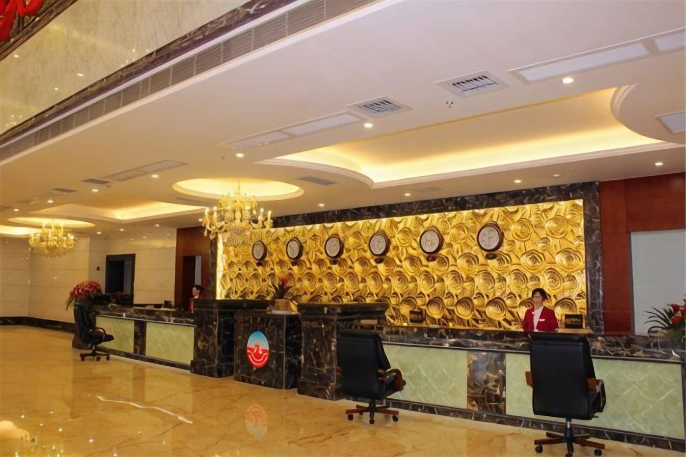 A hotel reception area with a marble floor, a reception desk, and a chandelier.