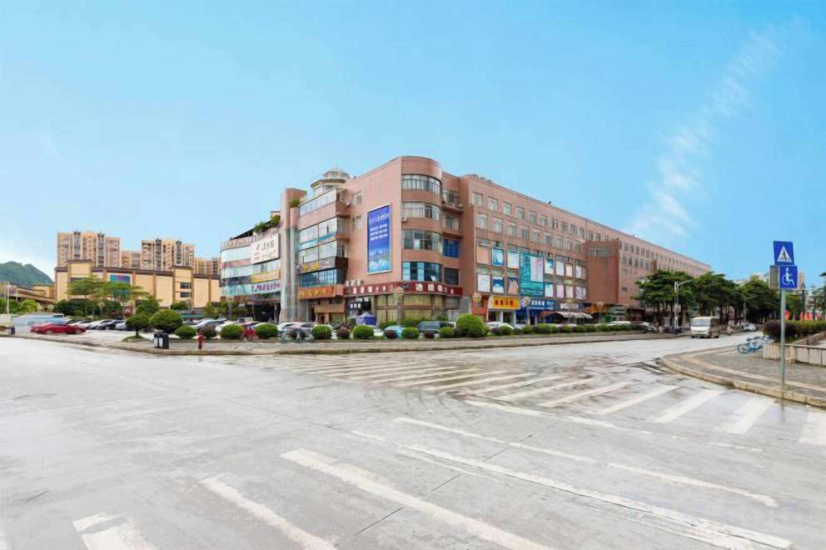 A multi-story building with commercial signage, a pedestrian crossing, and a clear sky.