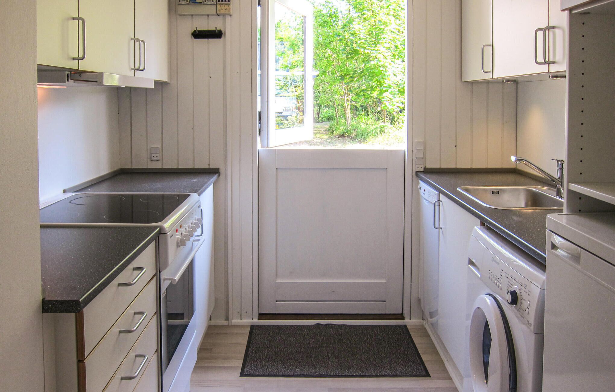 A compact kitchen with a stove, sink, and washing machine.