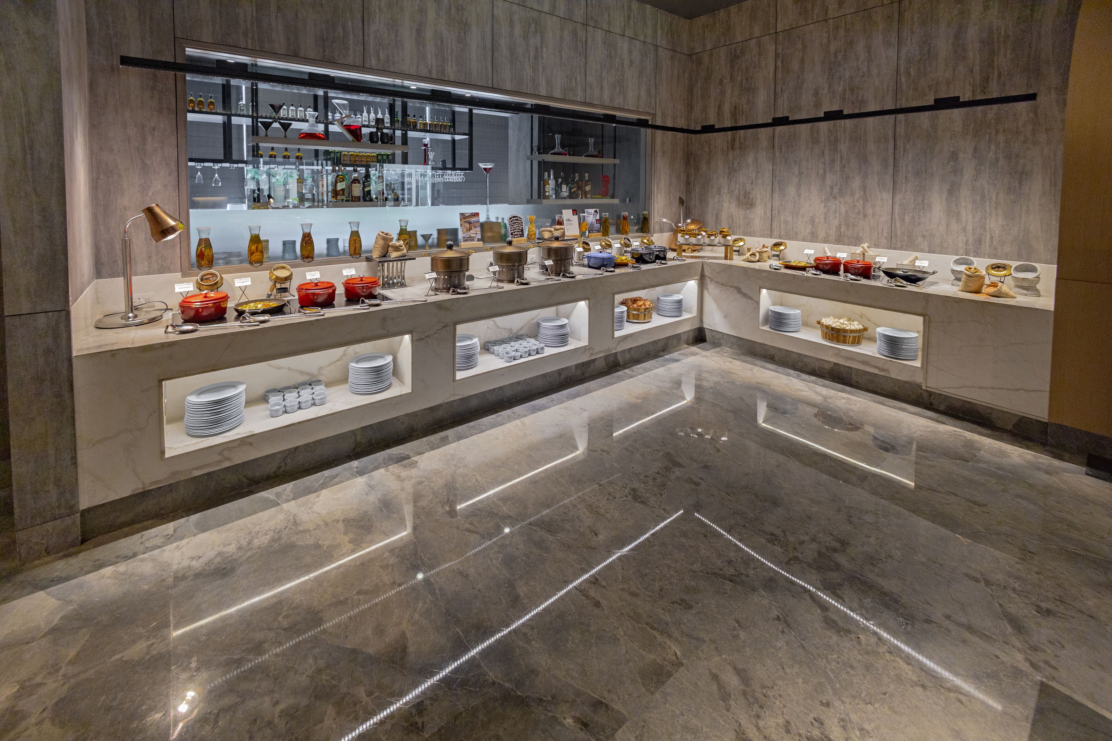 Un moderno vestíbulo de hotel con suelo de mármol, una recepción y una exhibición de utensilios de cocina y artículos para el comedor.