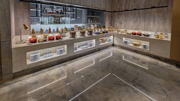 Un moderno vestíbulo de hotel con suelo de mármol, una recepción y una exhibición de utensilios de cocina y artículos para el comedor.