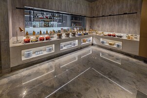 Un moderno vestíbulo de hotel con suelo de mármol, una recepción y una exhibición de utensilios de cocina y artículos para el comedor.