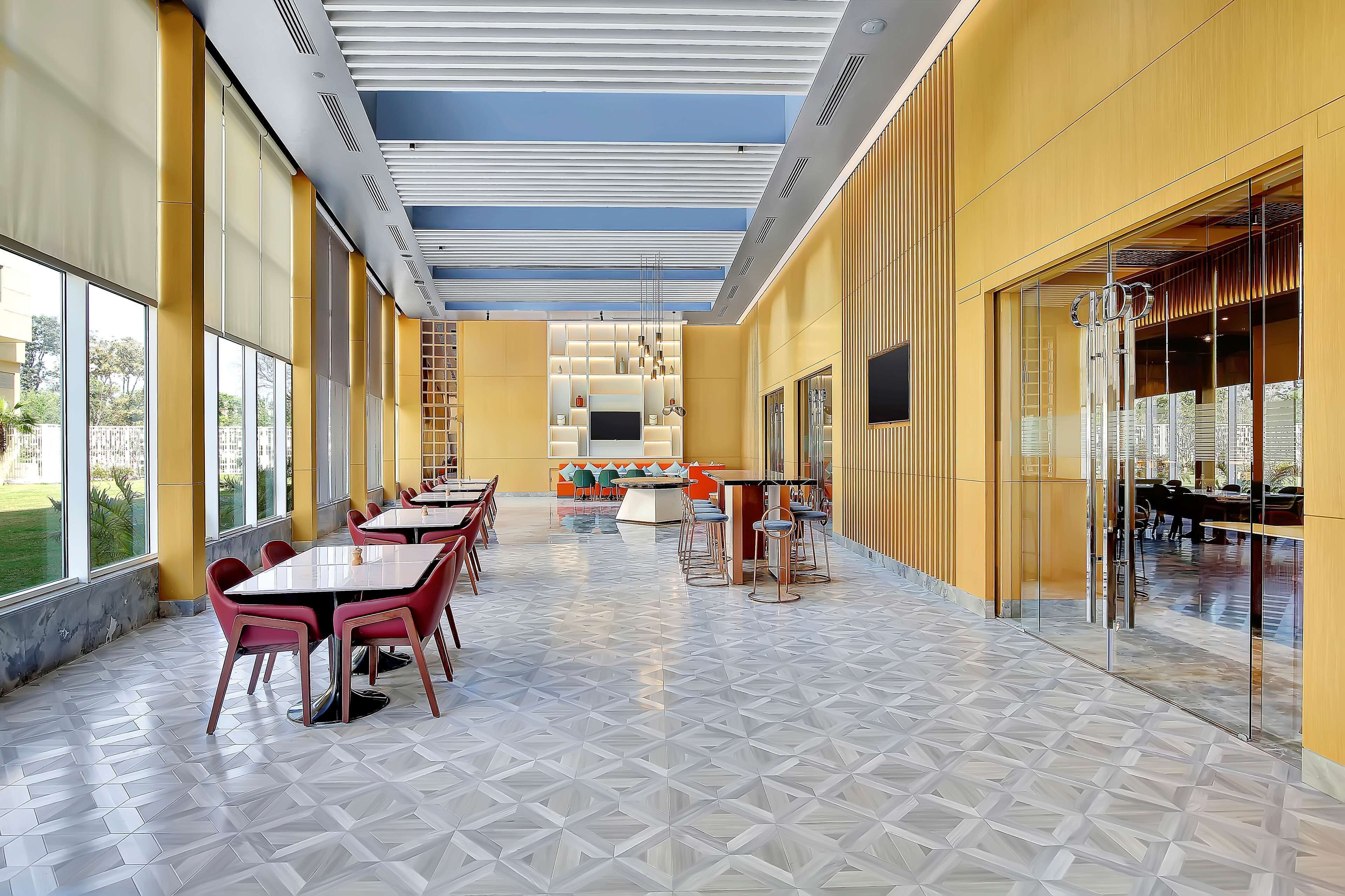 A spacious indoor area with a long table and chairs, a TV, and a seating area with a patterned floor.