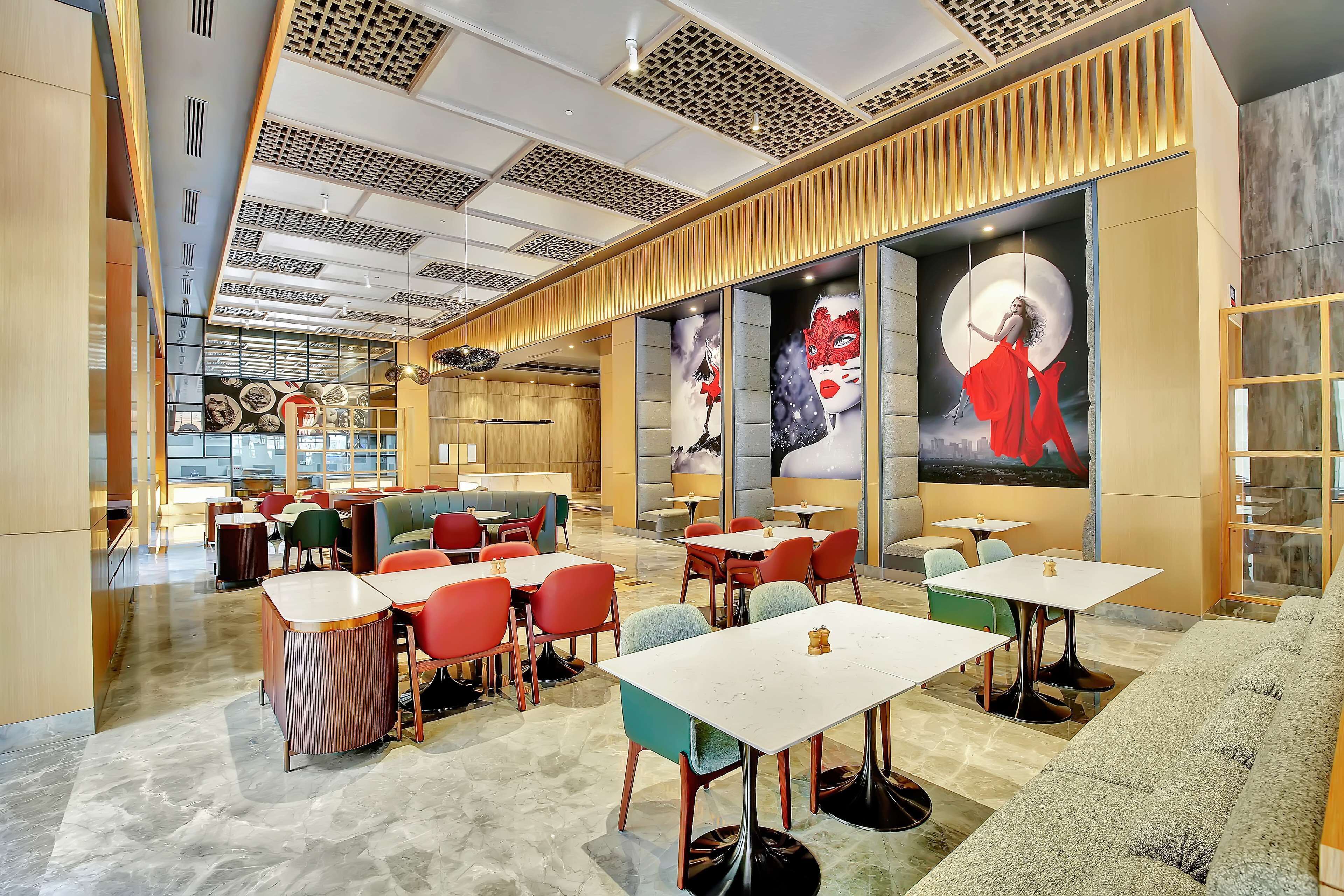 A modern restaurant with a variety of seating options, including tables and booths, and a large mural on the wall.