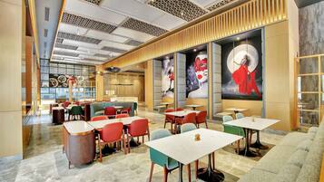 A modern restaurant with a variety of seating options, including tables and booths, and a large mural on the wall.