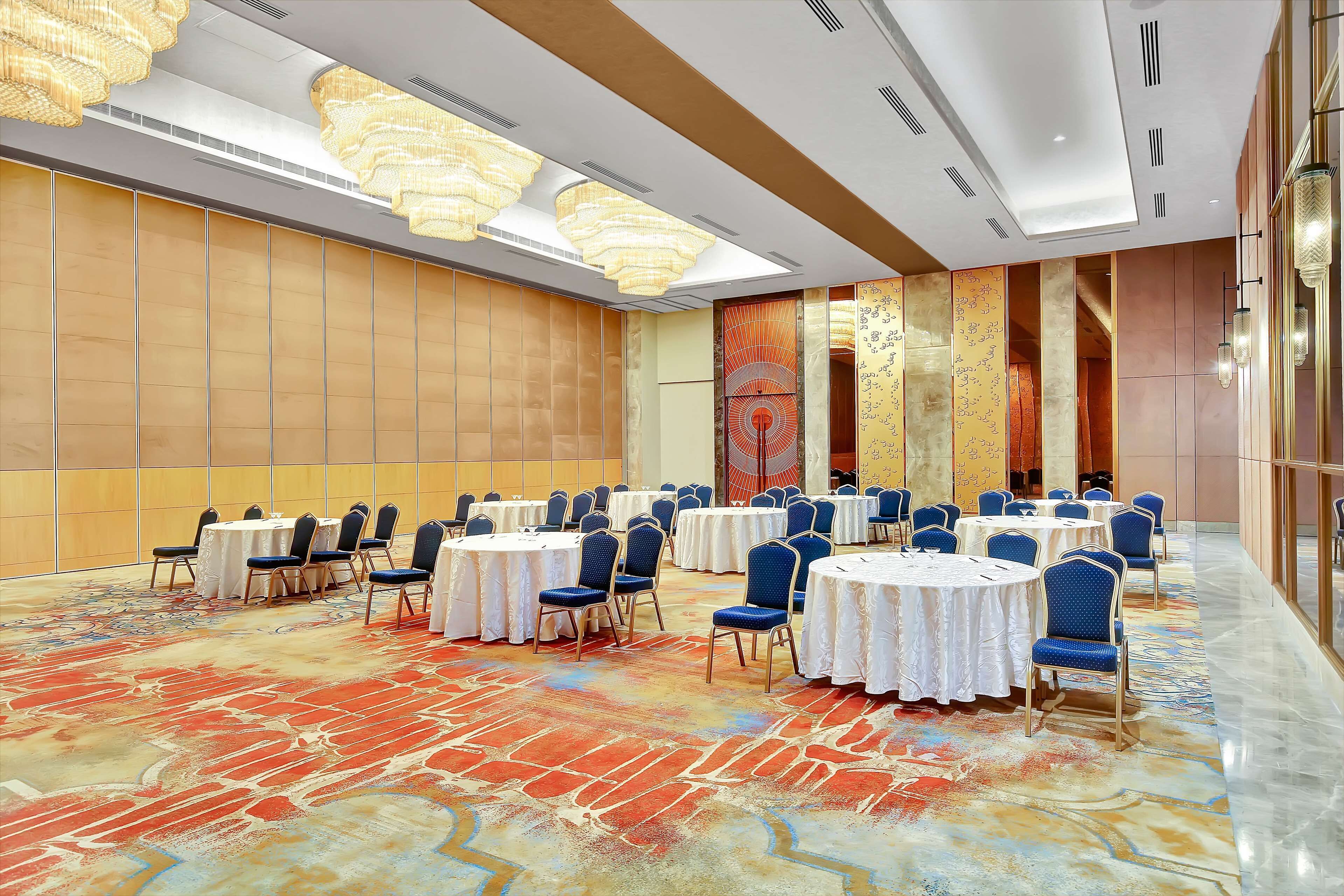 A conference room with round tables, blue chairs, and a patterned carpet.