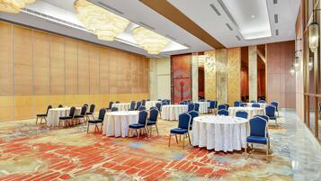 A conference room with round tables, blue chairs, and a patterned carpet.