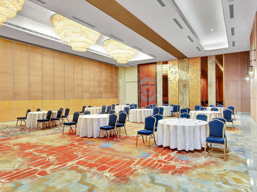 A conference room with round tables, blue chairs, and a patterned carpet.