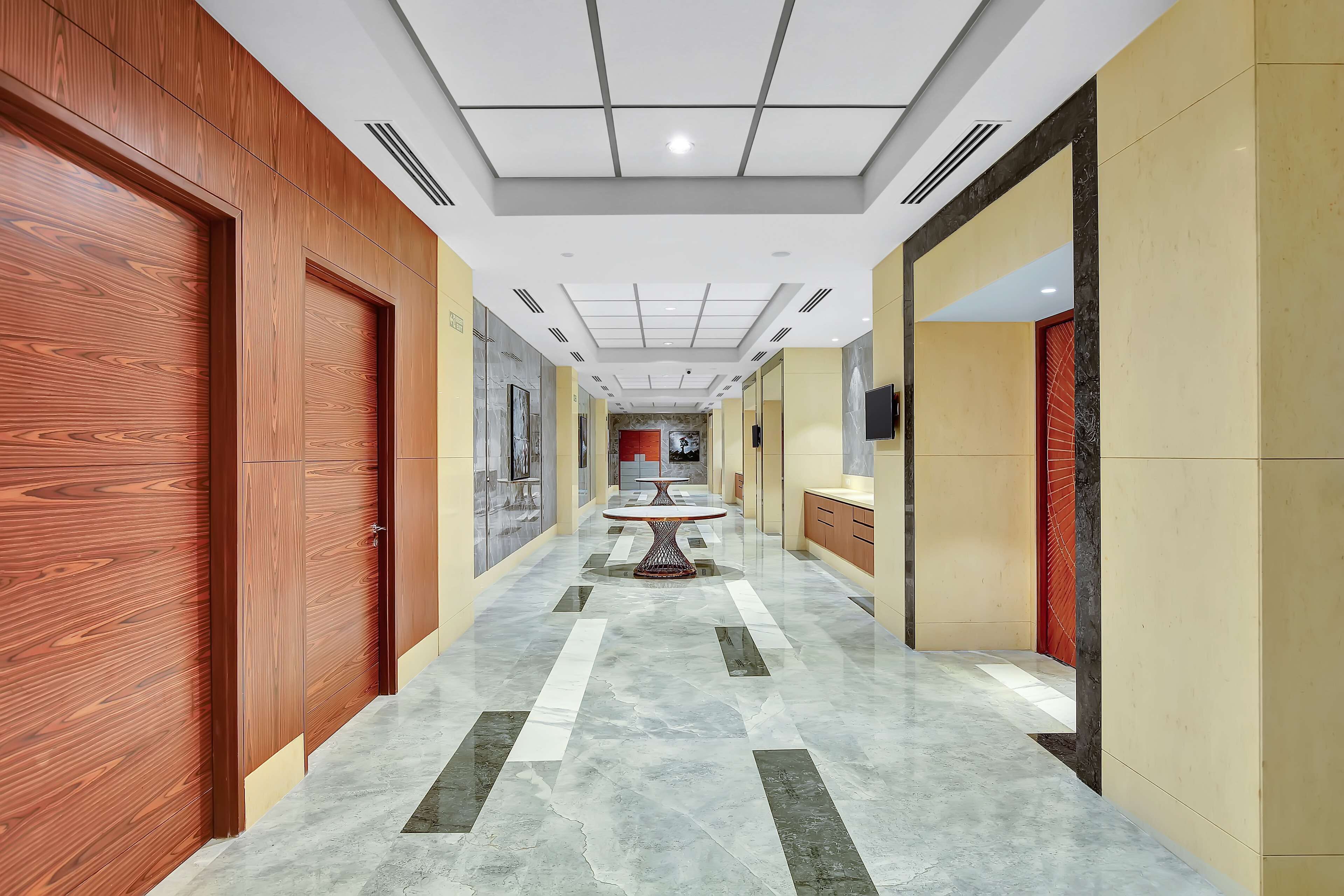A hallway with wooden doors, a marble floor, and a central table.