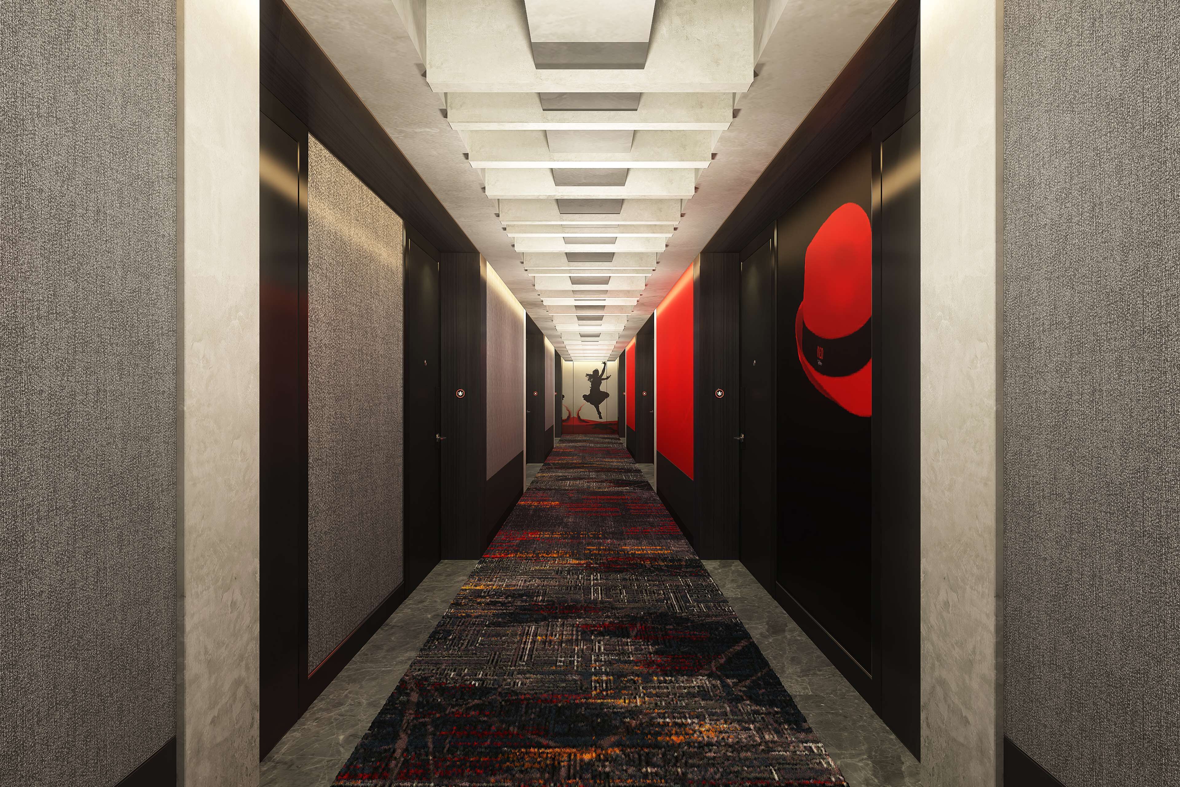 Passadís modern d'hotel amb una catifes estampada, parets fosques i una paret vermella d'accentuació.