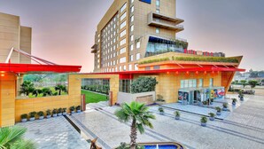 A modern hotel with a prominent RED sign, a landscaped entrance, and a pool area. - Radisson Red Chandigarh Mohali (Mohali)