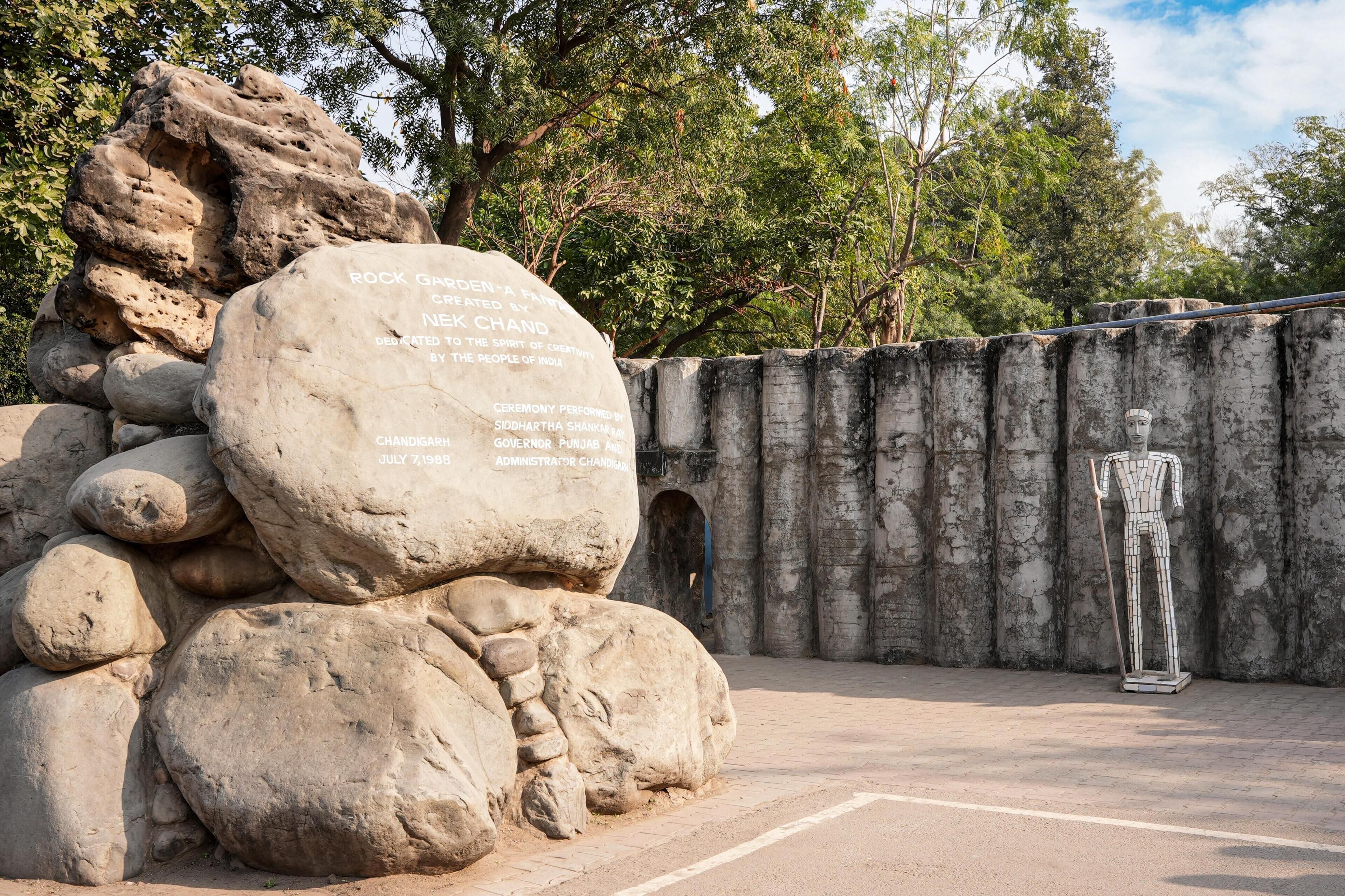 A large rock with inscriptions, a statue, and a stone wall with carvings.
