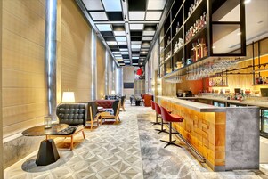 Un moderno bar con una barra larga, asientos y un suelo estampado.