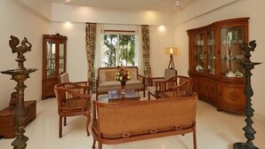 A traditional living room with a sofa, chairs, a coffee table, and a cabinet. - Maroma Suites (Chennai)