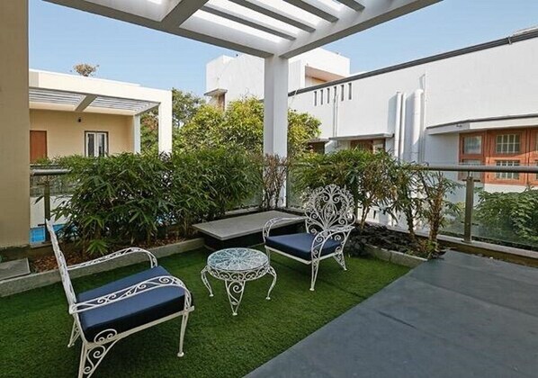 A rooftop terrace with a seating area, artificial grass, and surrounding greenery. - Maroma Suites (Chennai)