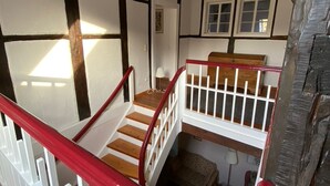 Un escalier avec une rampe rouge menant à un palier situé au deuxième étage.