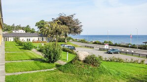 A coastal road with a view of the sea, a row of houses, and parked cars. - Cozy apartment in Allinge with WiFi (Allinge)