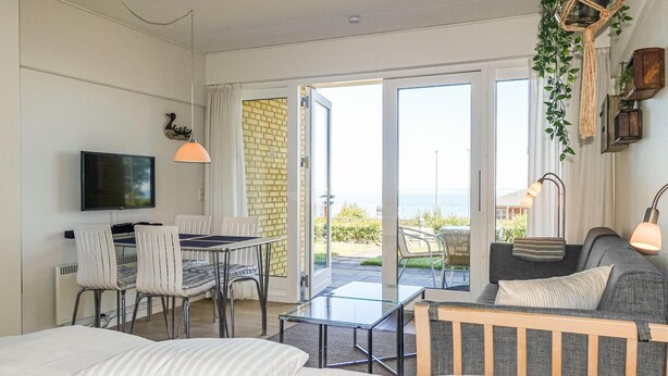 A modern room with a bed, a TV, a dining area with chairs and a table, a sofa, and a balcony with a view. - Cozy apartment in Allinge with WiFi (Allinge)