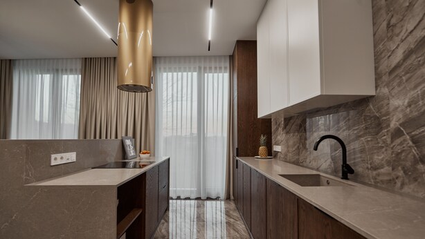 Una cocina moderna con encimeras de mármol, armarios de madera y una isla central.