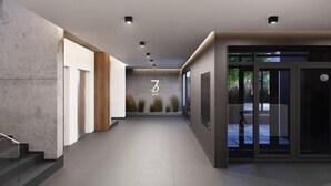 Un pasillo moderno con una escalera a la izquierda, un área de recepción con un logotipo en la pared y una puerta de cristal a la derecha.