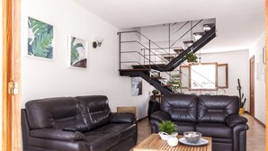 A living room with two black leather sofas, a wooden coffee table, and a staircase with a black railing.
