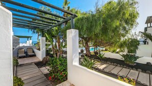 A patio area with a pergola, seating, and a view of a pool.