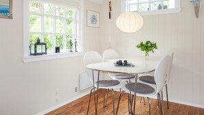 A dining area with a round table, white chairs, and a hanging light fixture. - 1 bedroom stunning home in Nexø (Nexø)
