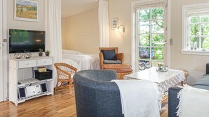 A cozy room with a bed, a television, a wicker chair, and a table with a vase. - 1 bedroom stunning home in Nexø (Nexø)