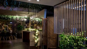 Un espace intérieur moderne comprenant un comptoir d’accueil, un coin salon et des plantes.