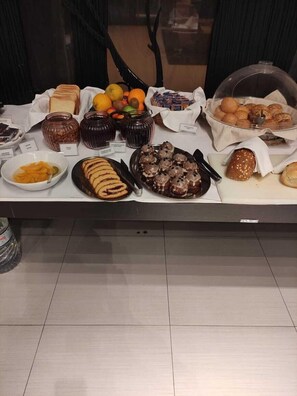 Ein Buffet mit verschiedenen Speisen, darunter Brot, Gebäck und Obst.
