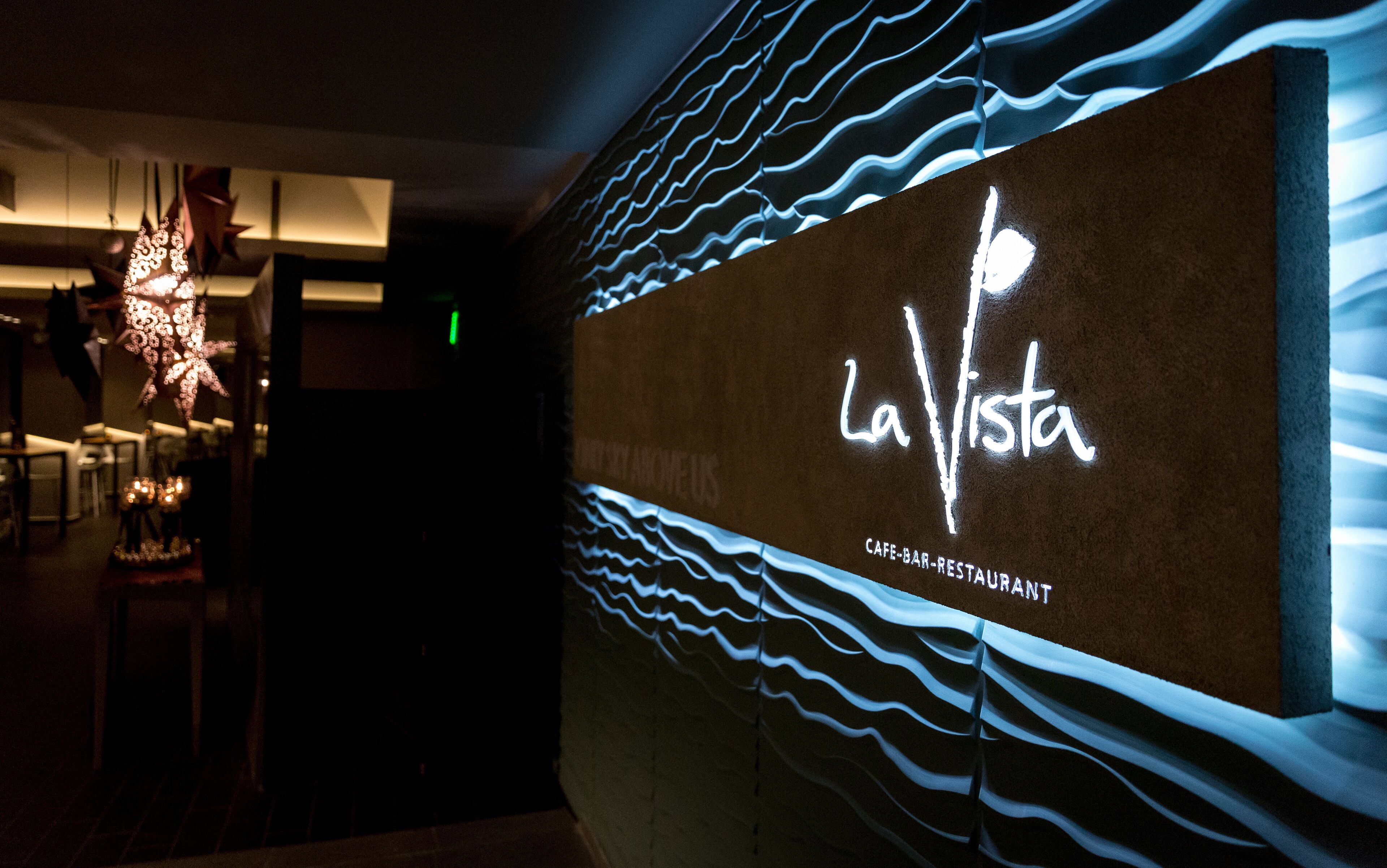 Pared con un letrero de neón que dice "La Vista" y "CAFÉ-BAR-RESTAURANTE", indicando un restaurante.