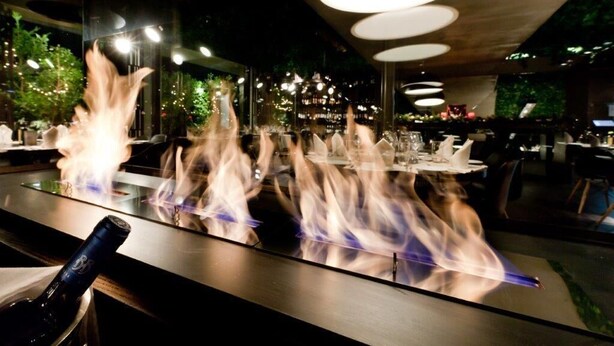 L’intérieur d’un restaurant moderne, avec un bar doté d’une table à plateau en verre et d’une bouteille de vin.