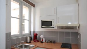 Een keuken met een spoelbak, een magnetron, een waterkoker en een koffiezetapparaat.