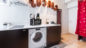 A compact kitchen with a washing machine, a microwave, and a coffee maker on the counter. - Charmant Studio Paris 15e Proche Tour Eiffel (Paris)