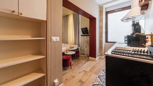 A compact kitchen with a gas stove, a coffee machine, and a small dining area with a table and chairs. - Charmant Studio Paris 15e Proche Tour Eiffel (Paris)